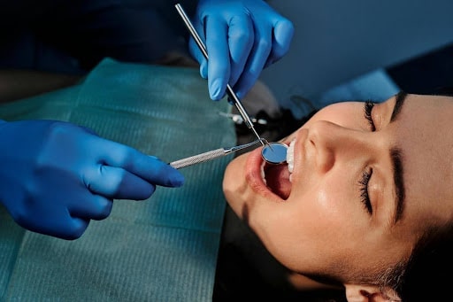 Dentist performing oral examination with mirror and dental probe Dentist performing oral examination with mirror and dental probe